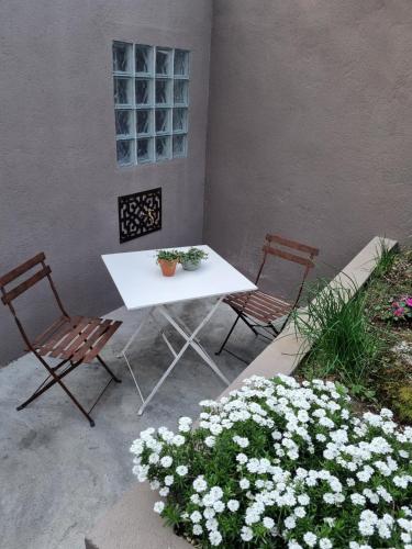 a white table and two chairs and some flowers at Entrerobles - Casiña Cereixa in La Cañiza
