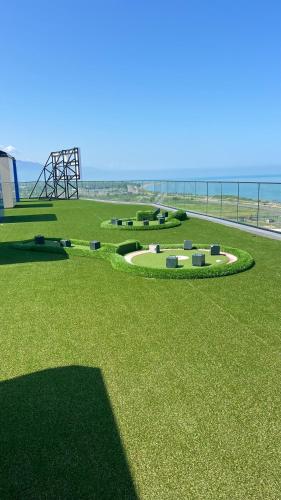 a grassy field with a park with a playground at у моря in Batumi