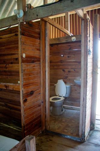a bathroom with a toilet in a wooden wall at Cabañas Wailidub, San Blas in Ogobsitupo