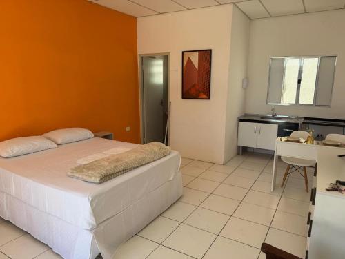 a bedroom with a bed and a desk and a kitchen at Golden Stay Suites in Jacareí