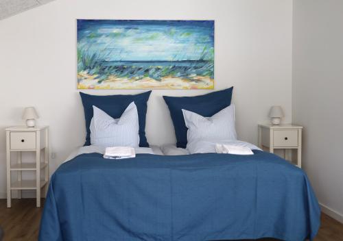 a blue bed with white pillows and a painting at Lønstrup Strandhotel in Lønstrup