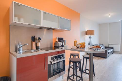 a kitchen with a sink and a table with stools at Le Doumer - Centre-ville - Petfriendly in Château-Gontier