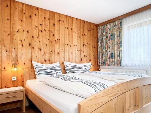 a bed in a room with a wooden wall at Haus Schönblick in Bschlabs