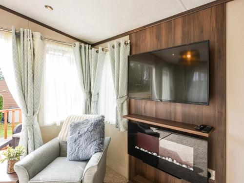 a living room with a tv on a wall at Avon Lodge in Hyssington