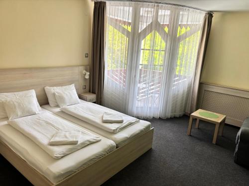 a bedroom with two beds and a large window at Grantek Üdülőház in Balatonlelle