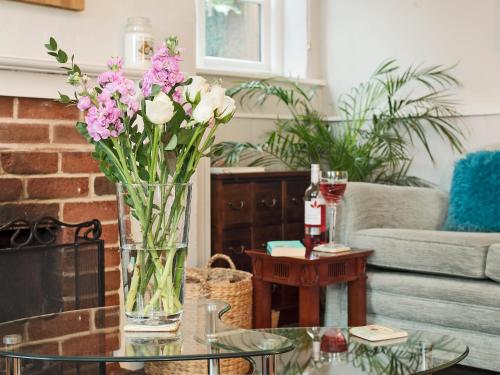 a vase of flowers on a glass table in a living room at Horseshoe House - Ukc2743 in Watton