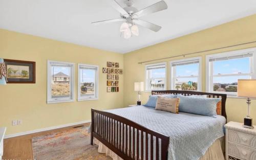 a bedroom with a bed with a ceiling fan and windows at Mischief Managed NC in Oak Island