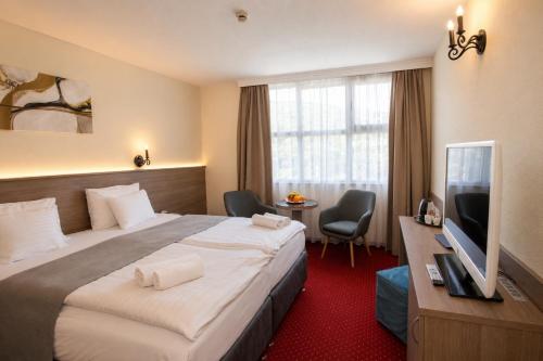 ein Hotelzimmer mit Bett und Flachbildfernseher in der Unterkunft Hotel Mediterran Budapest in Budapest