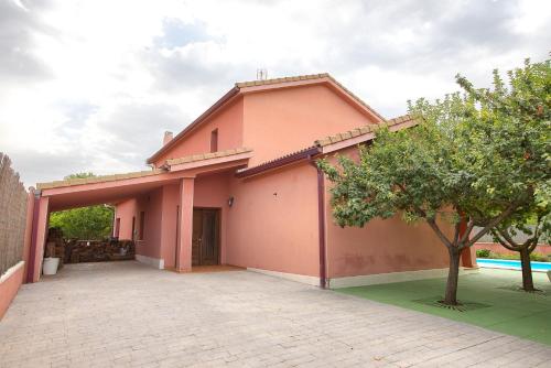 a pink house with a driveway in front of it at Cuencaloft Villa Los Perales in Villalba de la Sierra