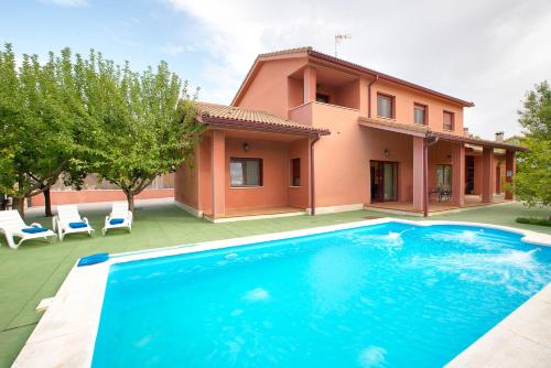 a villa with a swimming pool in front of a house at Cuencaloft Villa Los Perales in Villalba de la Sierra