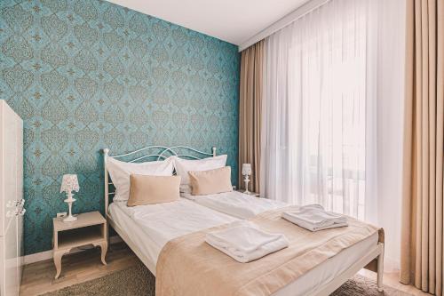 a bedroom with a bed with a blue wall at Maritimo Apartament przy Porcie by 2HomeRent in Kołobrzeg
