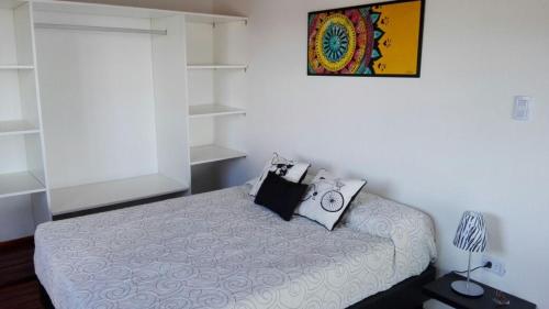 1 dormitorio con 1 cama con reloj en Duplex la Delfina 1 en Villa Carlos Paz