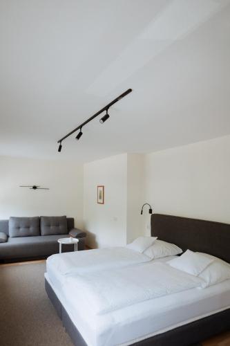 a bedroom with a white bed and a couch at Hotel Am Waldschwimmbad in Bürstadt