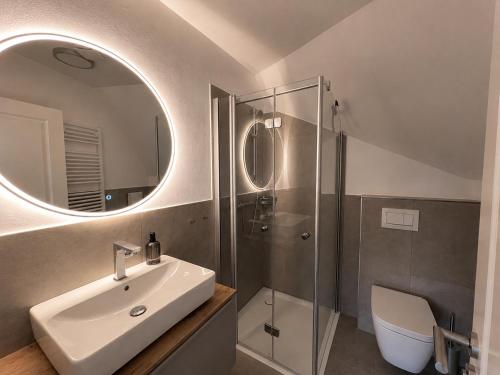 a bathroom with a sink and a shower with a mirror at elf-36 Apartmenthaus Bensersiel in Bensersiel