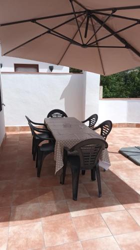 a table and chairs under an umbrella on a patio at Casa Benzambra in Cádiar