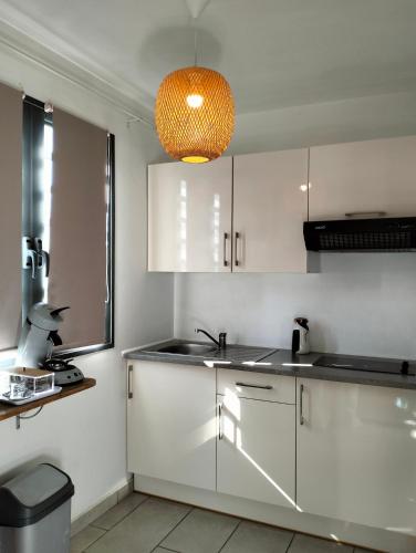 a kitchen with white cabinets and a light fixture at Cote Plage in La Saline les Bains