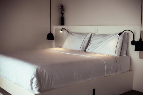 a bed with white sheets and a light on it at Kibuye House in Kibuye
