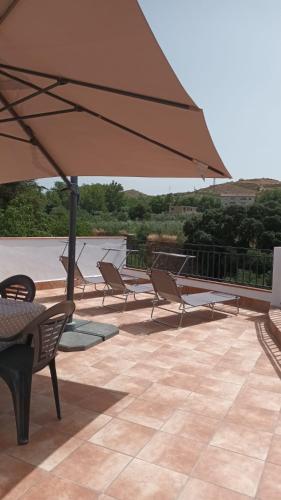 a group of chairs and an umbrella on a patio at Casa Benzambra in Cádiar