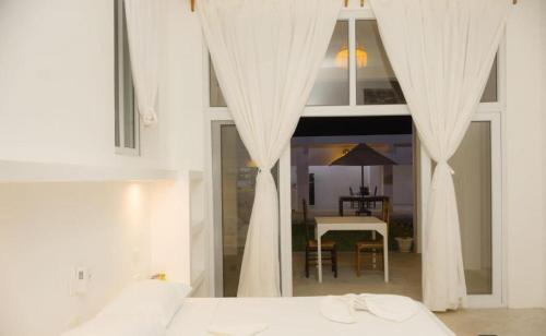 a bedroom with white drapes and a table and a dining room at Lilo House in Watamu