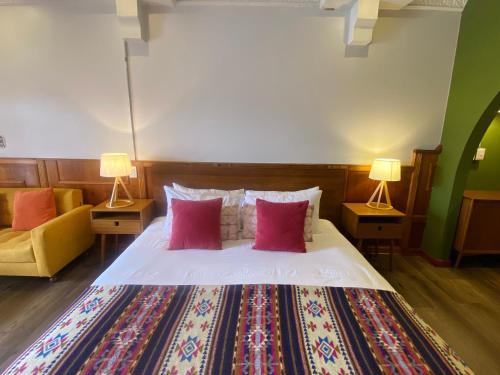 a bedroom with a bed with red pillows and two lamps at Cavi Rooms 511 in Cuenca