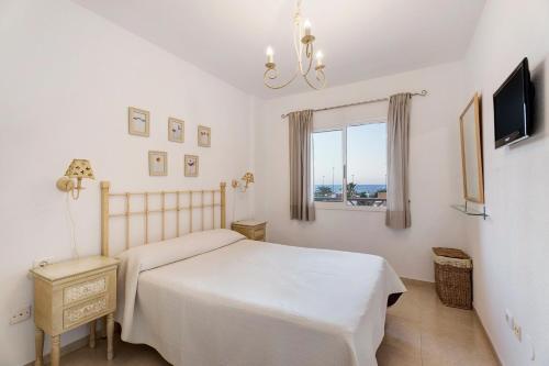 a bedroom with a bed and a tv and a window at Residencial La Gomera in Puertito de Güímar