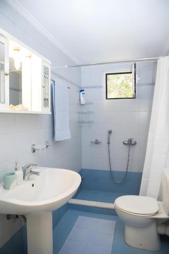 a white bathroom with a sink and a toilet at Evoia Village House in Neokhórion