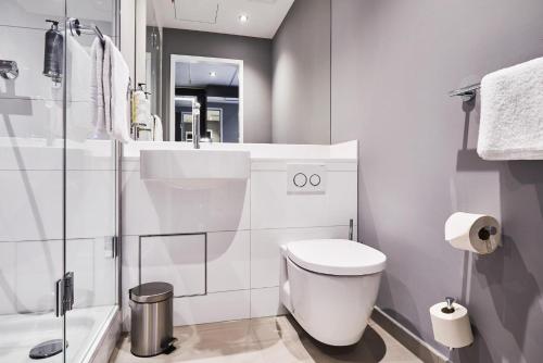 a white bathroom with a toilet and a shower at Premier Inn Köln City Mediapark in Cologne