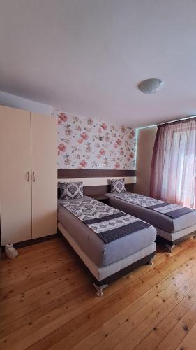 a bedroom with two beds and a cabinet and wood floors at Апартамент ГЕТО - 2 Комфорт in Belogradchik