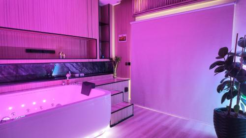 a pink bathroom with a tub and a plant at جناح فاخر بإطلالة على البحيرة وجاكوزي خاص in Al Khobar