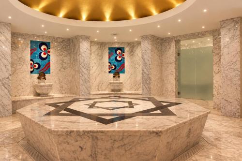 a lobby with a large marble table with paintings on the walls at Sheraton Istanbul Atakoy Hotel in Istanbul