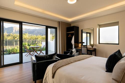 a bedroom with a large bed and a balcony at Kleine Banhoek Manor in Stellenbosch