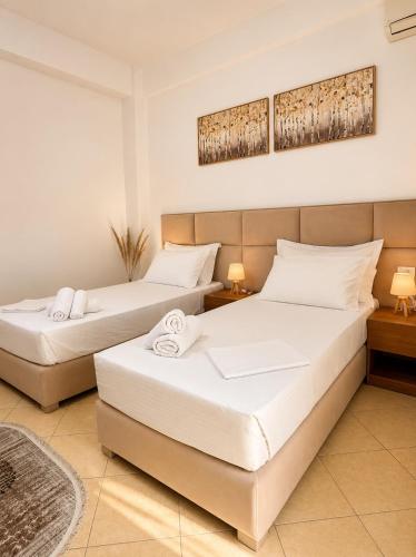 two beds in a hotel room with white sheets at Guesthouse Zisi in Gjirokastër