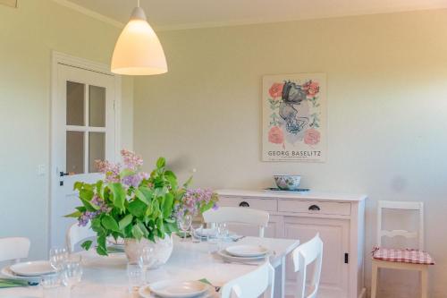 ein Esszimmer mit einem Tisch und einer Vase mit Blumen in der Unterkunft Ferienwohnung Koppelblick III - Boldevitzer Rügenkaten in Parchtitz