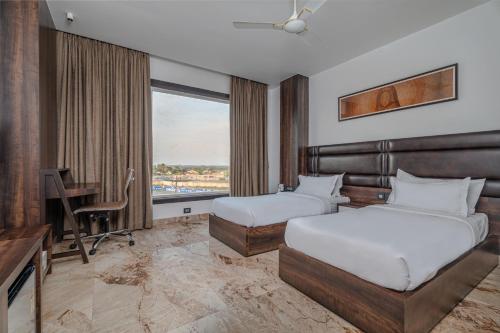 a bedroom with two beds and a desk and a window at ECONEST HOTEL in Tarapith