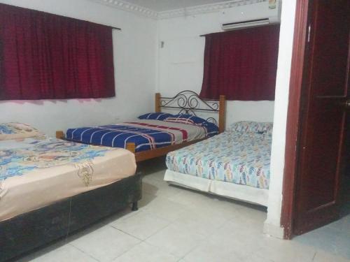 two beds in a room with red curtains at Reina Elizabeth I in Santa Marta