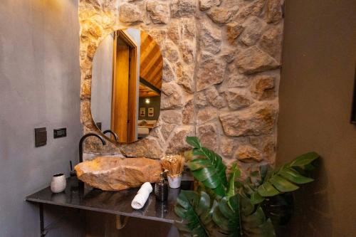 a bathroom with a stone wall and a table with a mirror at GRETEL CHALETS SUIZO in Guatapé