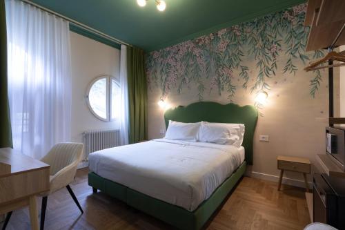 a bedroom with a bed with a green headboard and floral wallpaper at VILLA UGO b & b in Salsomaggiore Terme
