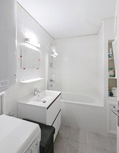a white bathroom with a sink and a tub at Evasion in Orcières