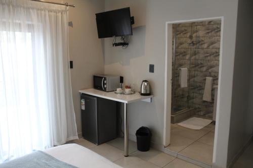 a bathroom with a sink and a shower with a microwave at Kanyane @ Graskop in Graskop