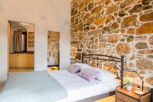 a bed in a room with a stone wall at Vlychos Olympi Lodges - Chios Cozy Getaways in Olýmpoi