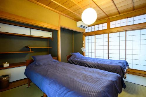 un dormitorio con dos camas y dos ventanas en KOAのお宿 ー Koa no Oyado ー, en Gujō