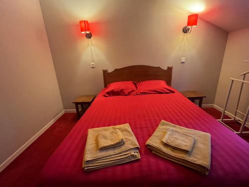 a bedroom with a red bed with two towels on it at Valentine in Monflanquin
