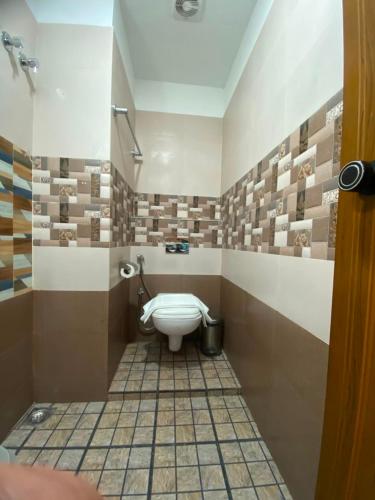 a bathroom with a toilet in a room with tiles at Nova Alhind Airport Hotel Cochin in Nedumbassery
