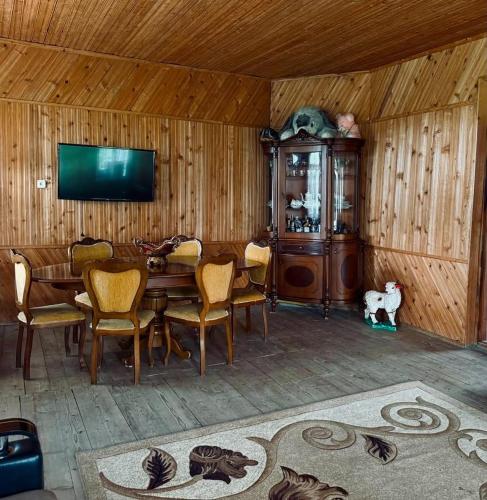 a dining room with a table and chairs and a television at Mamuka's Villa in Tsqaltsminda