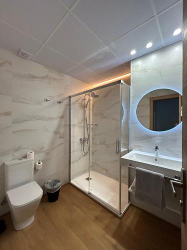 a bathroom with a shower and a toilet and a sink at Apartamentos El Jardín de Isla Autocheck-In in Isla