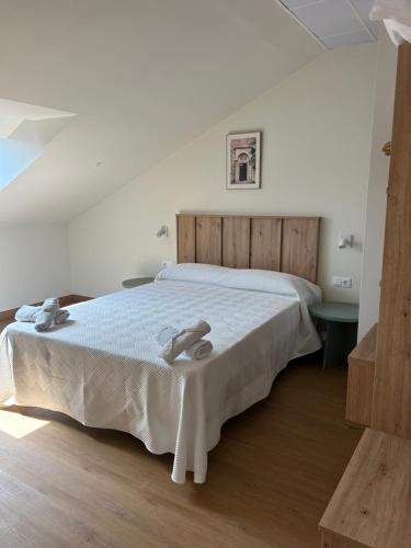 a bedroom with a white bed with a wooden headboard at Apartamentos El Jardín de Isla Autocheck-In in Isla