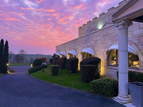 a building with bushes in front of a sunset at Le Royal Picardie, BW Signature Collection in Albert