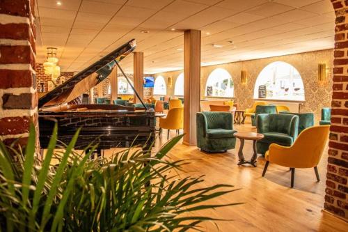 a lobby with a piano and chairs and a table at Le Royal Picardie, BW Signature Collection in Albert