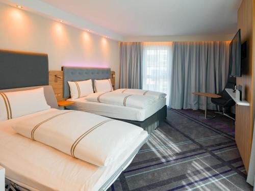 a hotel room with two beds and a desk at Premier Inn Mannheim City Centre in Mannheim