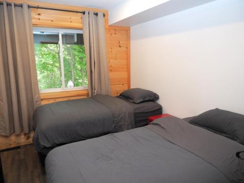 two beds in a room with a window at Renovated 6 Bedroom Chalet Hot Tub Near Village in Blue Mountains